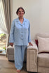 Elderly woman wearing a light blue linen pyjama set with elastic-waist pants and a comfortable button-up jacket for seniors.