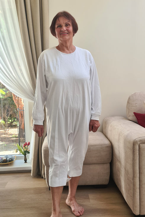 Elderly woman wearing a white geriatric pyjama with long sleeves, designed for seniors to provide comfort and ease of dressing.