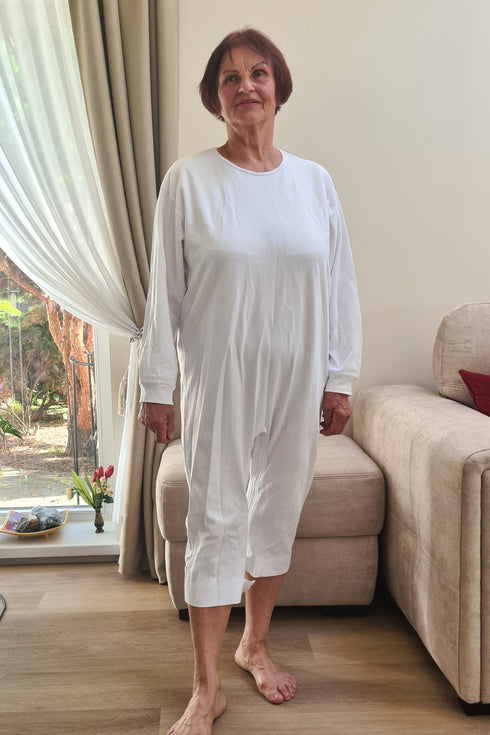 Adaptive white geriatric pyjama for seniors, modeled by an elderly woman, designed for convenience, comfort, and dignity in daily care.